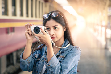 Portrait of an Asian woman smiling and take photo at the train station. Tourism concept