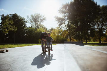 Naklejka premium Father Learning his son to ride a bicycle