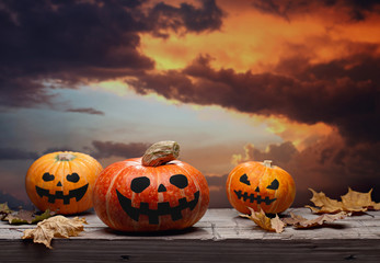 Halloween background, scary pumpkins on an old wooden surface. Ominous crimson sky. Spooky Halloween. Poster.