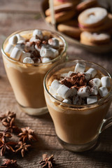 selective focus of cacao with marshmallow in mugs on wooden table with anise