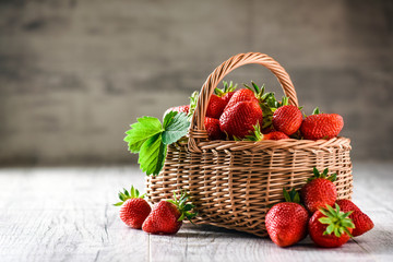 Fresh ripe strawberries in wicker basket on white rustic table. Copy space.