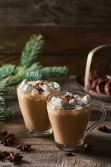 selective focus of cacao with marshmallow and cacao powder in mugs near pine branches, cinnamon and anise on wooden table