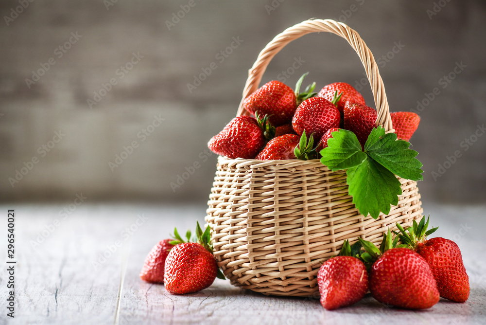 Wall mural red strawberries in small wooden basket or wicker. healthy fresh fruits on white table with copy spa