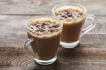 cacao with marshmallow and cacao powder in mugs on wooden table