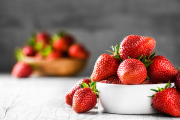 Fres pile of Strawberries in white porcelain bowl. Red strawberry in blur background.