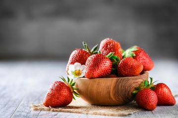 Nice fresh strawberries in wooden bowl. Juicy red forest fruits on table.