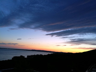 Yellow-pink sunset over the sea and the slope of the mountain overgrown with greenery