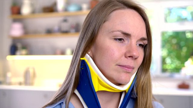 Woman Wearing Neck Brace At Home Winces With Pain