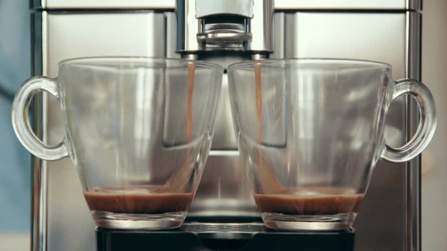 Preparation two natural delicious coffee simultaneously in the automatic coffee machine. Coffee is poured into cups. Good morning. 
