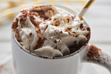 close up view of Christmas cacao with cacao powder and whipped cream in mug with straw