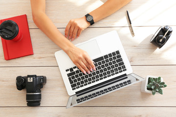 Young female photographer working on laptop at table
