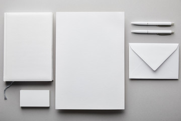 top view of paper, notebook, pens, business card and white envelope
