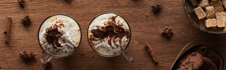 top view of Christmas cacao with whipped cream on wooden table near cookies and brown sugar, panoramic shot