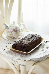 Tea service with banana bread over a white table cloth in front of a window