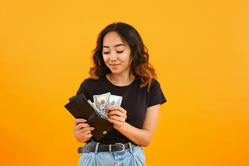 Asian woman putting money into wallet on color background - obrazy, fototapety, plakaty
