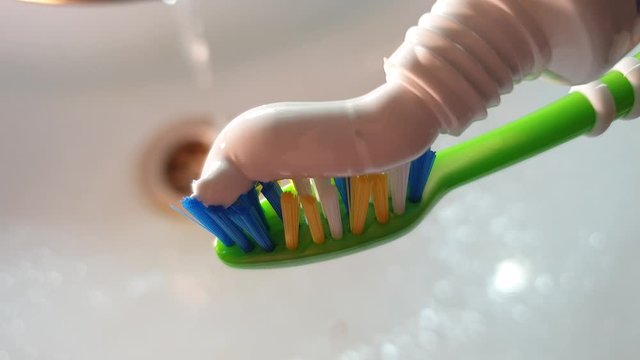 Squeezing toothpaste onto a toothbrush.