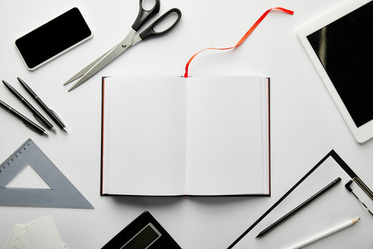 top view of clipboard, notebook, pens, pencils, scissors, triangle ruler, calculator, smartphone and digital tablet