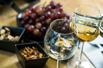 Pouring white wine into the glass against wooden table