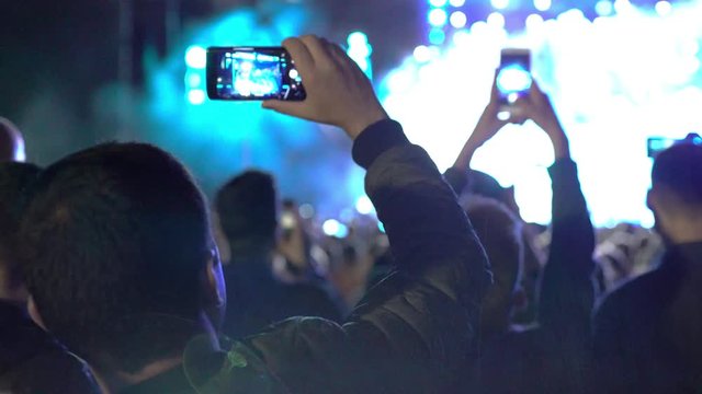 Concept view of young people filming concert of their favourite musician band youth rave party concert stage live techno 4k