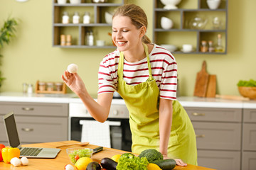 Beautiful young woman cooking in kitchen