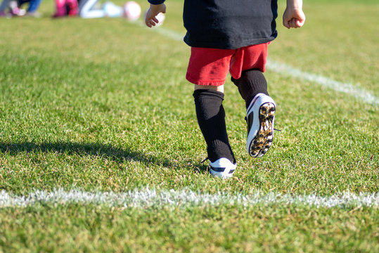 Blurred For Effect - Action Shot Of Young Kid In Cleats Running Onto Soccer Field