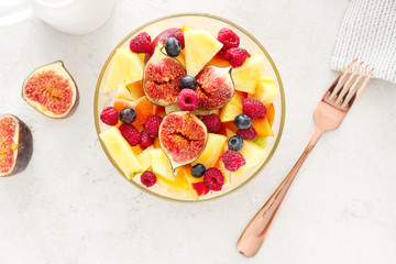 Bowl with tasty fruit salad on light background