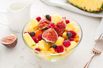 Bowl with tasty fruit salad on light table