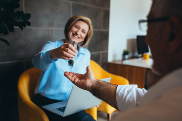 Obraz premium retail agent offering house keys a customer in office