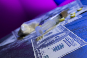 cocaine, dollars, pills and syringe on the table