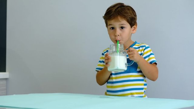 slow motion asian Cute little kid drinking milk on kitchen. cheerful boy likes to drink milkshake