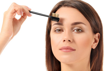Fototapeta premium Beautiful young woman with makeup brush on white background