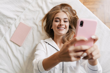 Cute girl in pajama at home on bed using mobile phone.