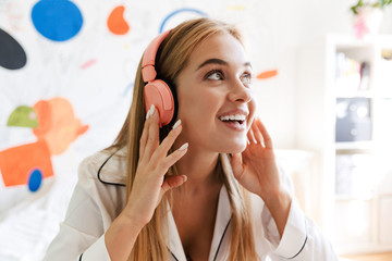 Cute girl in pajama at home on bed listening music