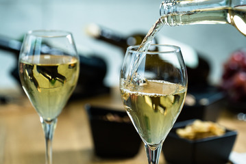 Pouring white wine into the glass against wooden table