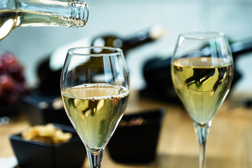 Pouring white wine into the glass against wooden table