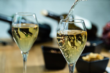 Pouring white wine into the glass against wooden table
