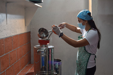 Woman pouring fermented alcoholic juice in stainless dispenser  in a home based winery. side view shot