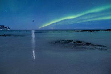 Beautiful northern lights over the snow covered winter landscape of the Lofoten islands