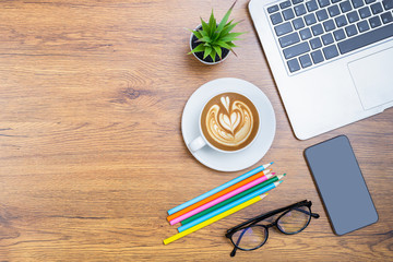 Wood office desk table with laptop, cup of coffee and supplies