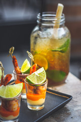 Classic cuban mojito with lime, mint and black sugar served in a big glass and prawn skewer tapas