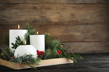 Beautiful Christmas composition with burning white candles on wooden background. Space for text