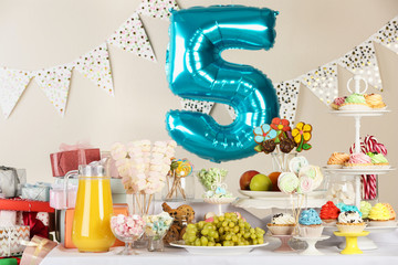 Blue number five balloon over table with delicious treats at Birthday party indoors