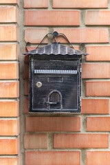 Old iron mailbox on a brick wall of a house. A tool for delivering paper correspondence.