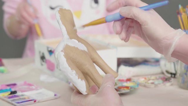 Painting with a white acrylic paint unicorn paper mache figurine.