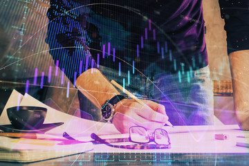 Double exposure of man writing on paper with forex graph.