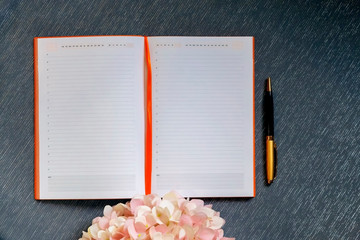 Flatlay with mockup. Notepad clean with a blank page for writing text, pen, pink hydrangea flowers on a gray background