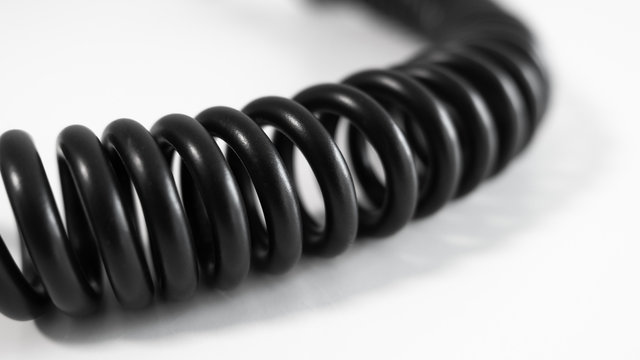 Black coiled cable on white table. Close up with shallow depth of field.