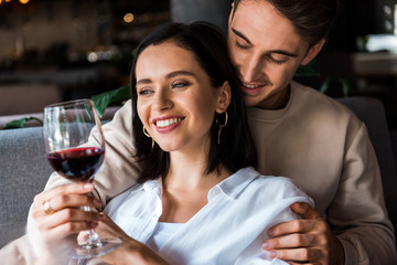 happy man looking at woman with glass of red wine