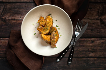 Roasted countryside styled potatoes on rustic dark wooden table