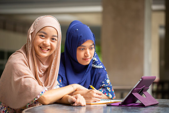 Two asian musalim working and discuss with tablet i